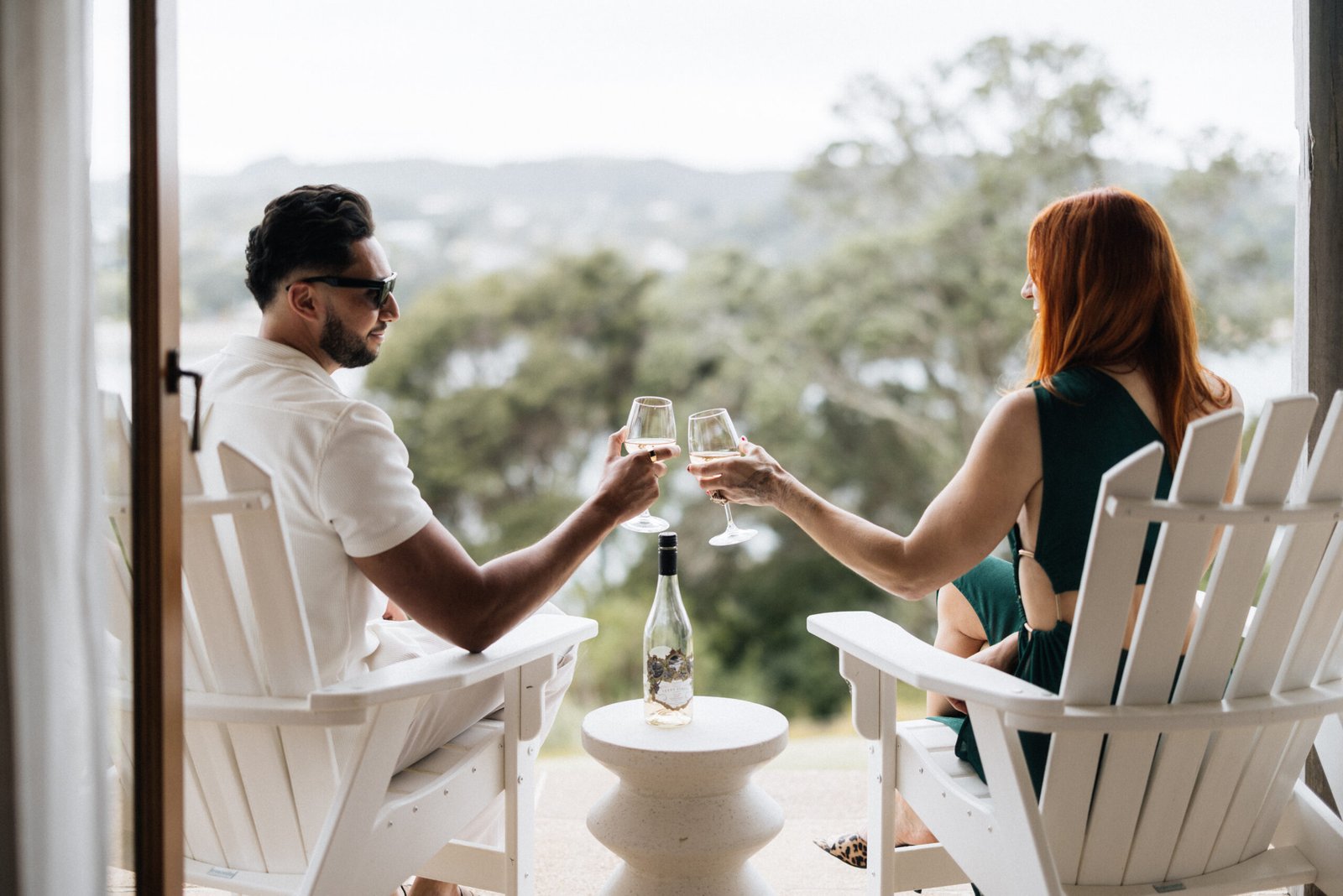 Couple enjoying a glass of wine outdoors at Putiki Estate, luxury accommodation on Waiheke Island